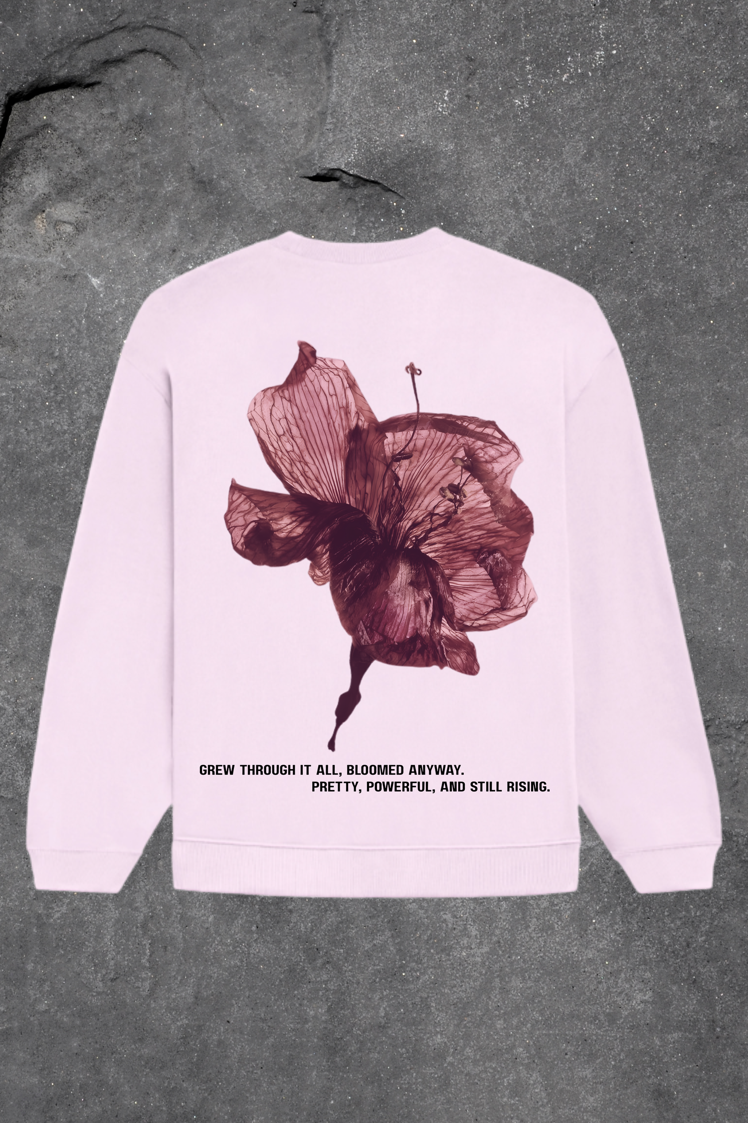 Baby  pink sweatshirt with a floral design and text on the back against a gray background