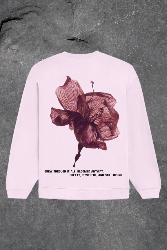 Baby  pink sweatshirt with a floral design and text on the back against a gray background